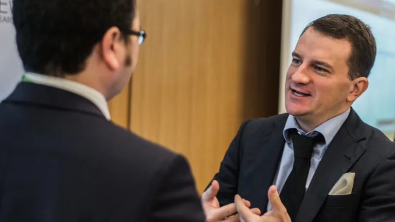 Two businessmen in suits talking at a networking event
